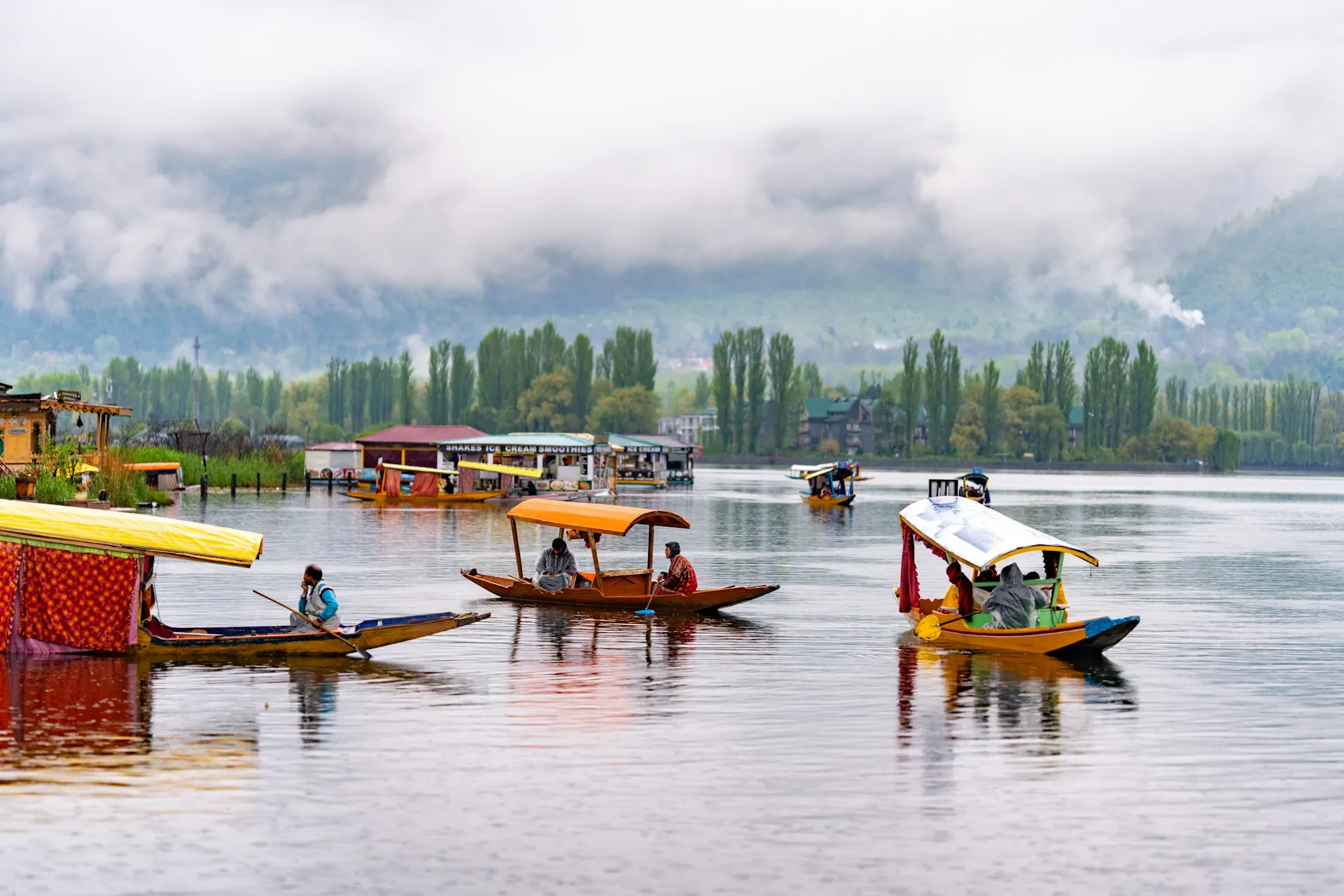 Traditional Shikaras on Dal Lake in Srinagar, Kashmir with the Zabarwan Mountains in the background.